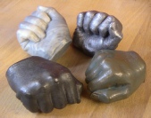 Life cast of a fist showing examples in Aluminium, Bronze, Iron Marble resin