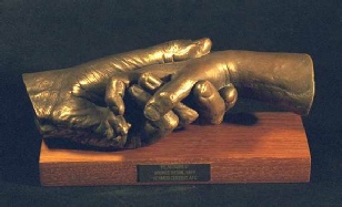 Reassured - life-size sculpture showing a child's hand supported and held securely yet tenderly in the father's hand